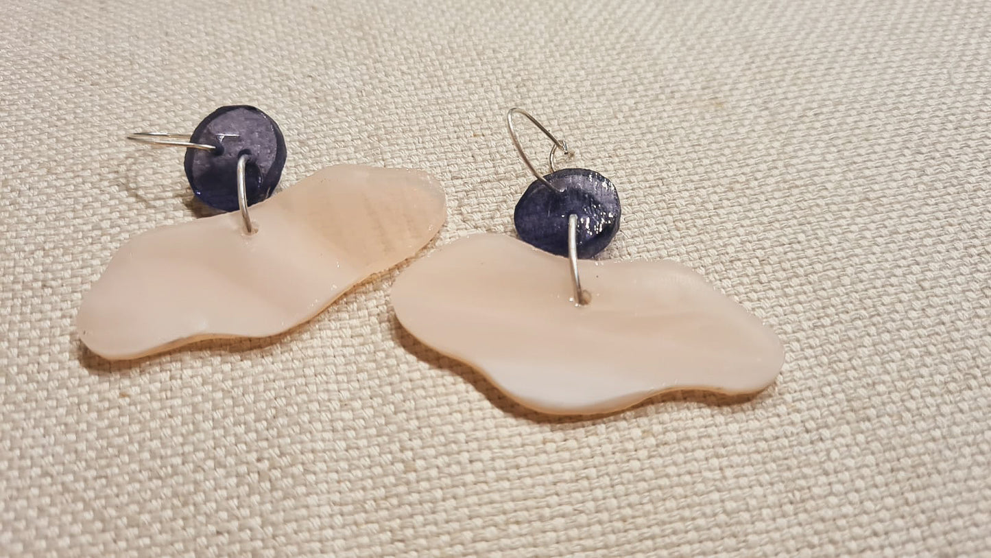 Ces boucles d’oreille présentent un disque violet mystique qui soutient une forme de nuage rose laiteux semi-opalescent. Elles sont agrémentées d’attaches crochet argentées en laiton. 