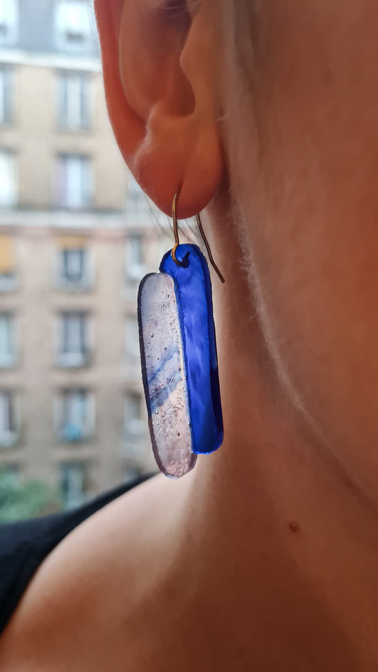 Ces boucles d’oreilles présentent deux verres de forme oblongue. L’un est bleu cobalt et l’autre présente un mélange de volutes rosées et bleutées sur fond clair. Le verre présente des bulles qui concourent à son charme :) Elles sont agrémentées d’attaches crochet en acier chirurgical. 